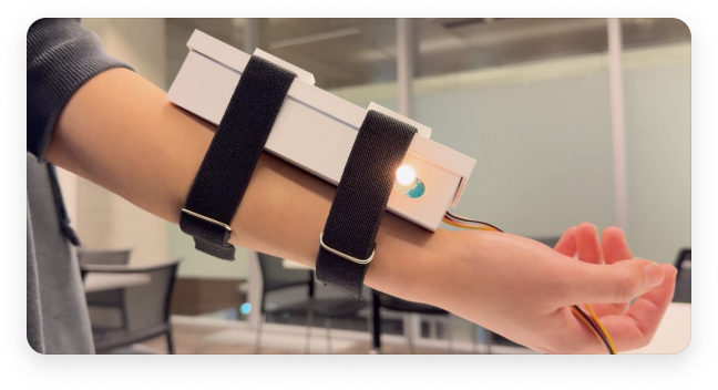 The finished device worn on a forearm, the box strapped on with the wand running off it